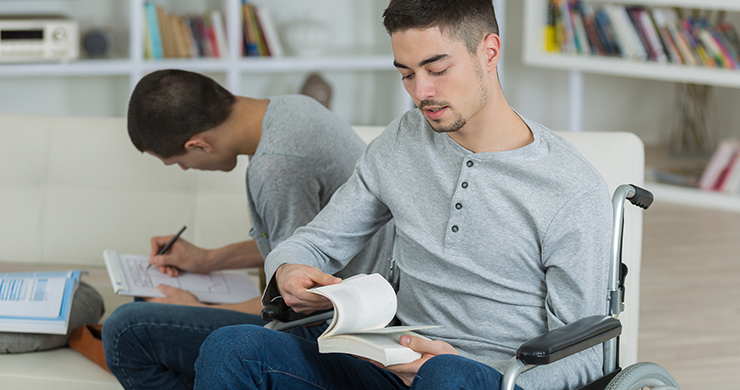 Man in wheelchair reading a book in the library