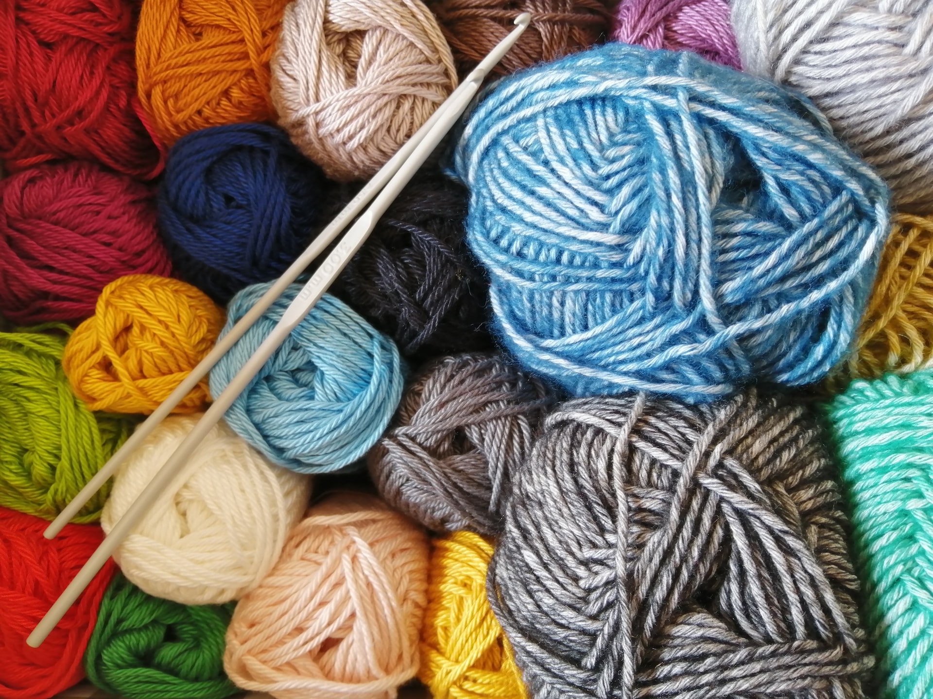 photo of balls of yarn in various colors with two crochet hooks