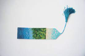 A blue and green watercolor bookmark with a blue tassel. 