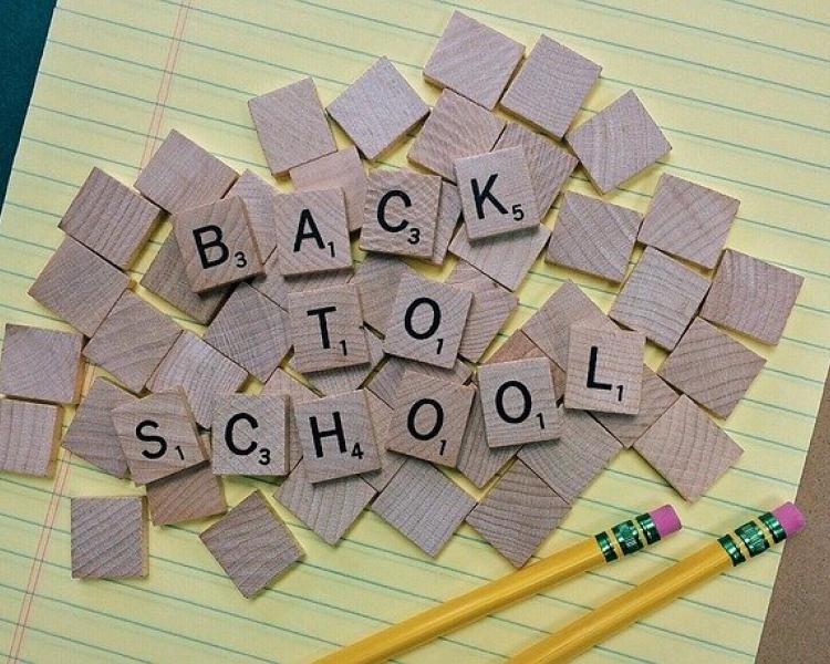 Back to School spelled with scrabble pieces on yellow notepad. 